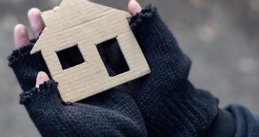 Hand met kartonnen huis erin