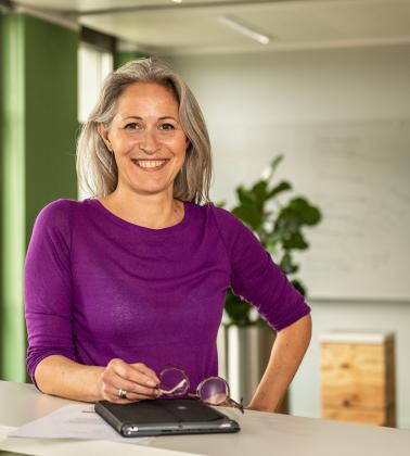 Mareike Naumann van Eigen Haard in een paarse trui op kantoor.