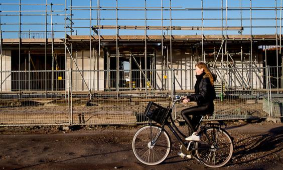 Meisje fietst langs nieuwbouw