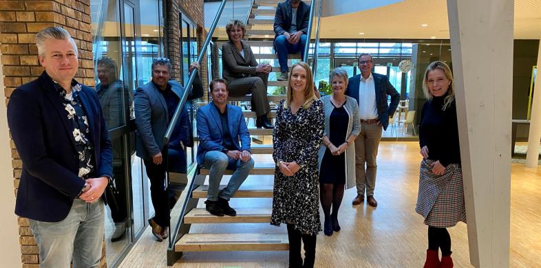 Vijvermanagementteam geposeerd op en rond een trap