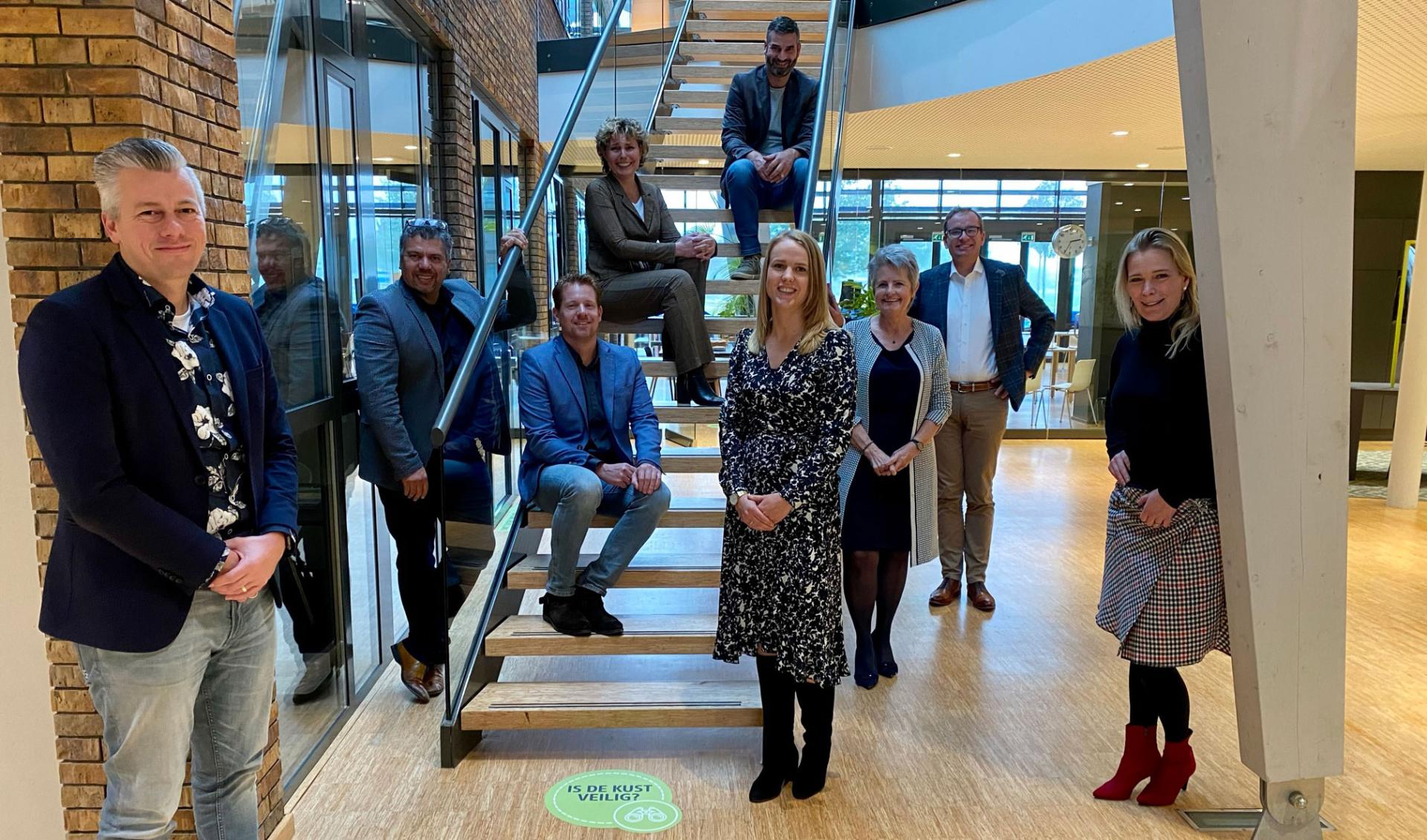 Vijvermanagementteam geposeerd op en rond een trap