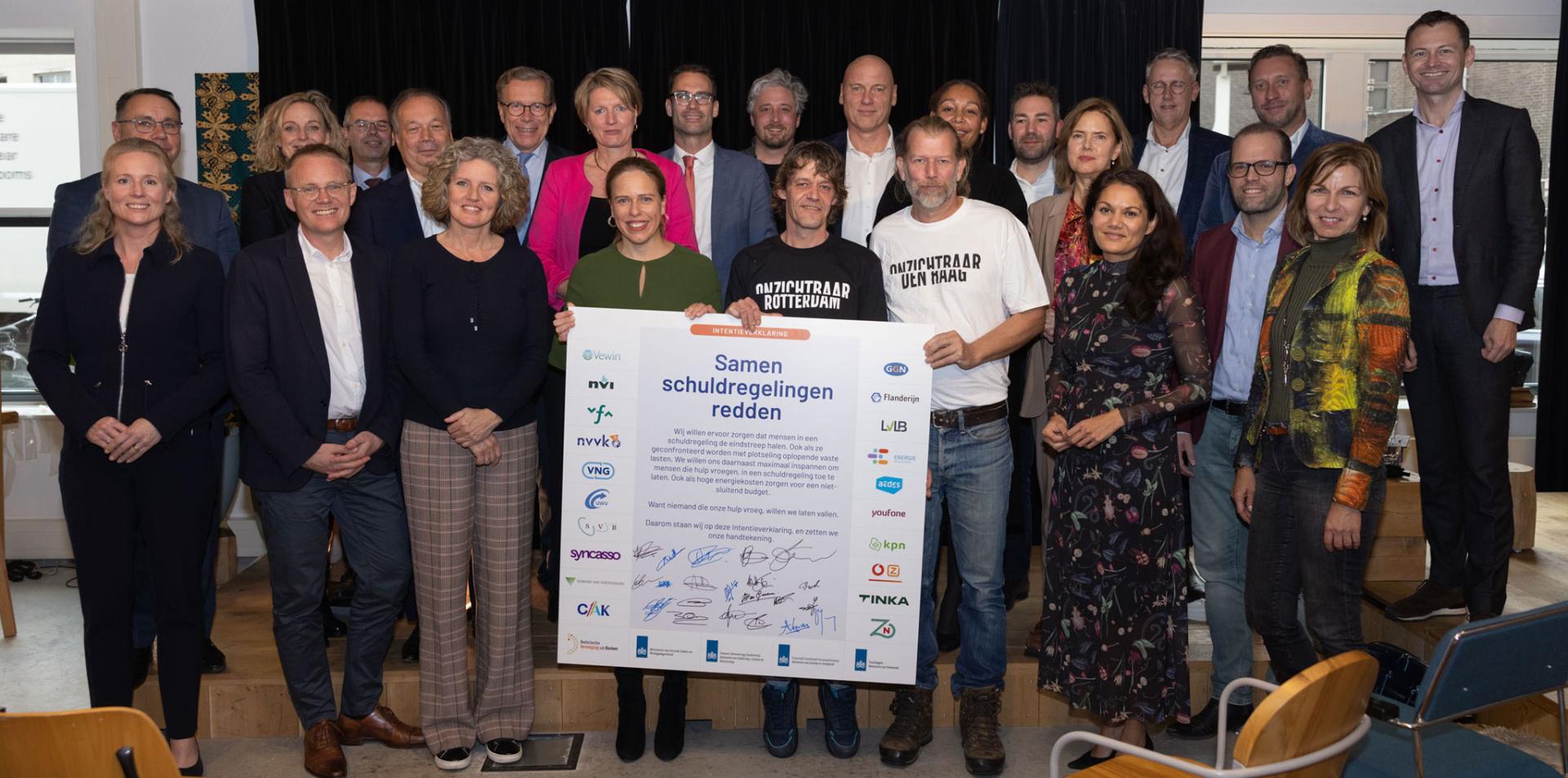 Groepsfoto van de ondertekenaars van de Intentieverklaring Samen schuldregelingen redden samen met 2 ervaringsdeskundigen